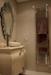 Baño con radiador toallero de acero y lavabo integrado en mueble de diseño